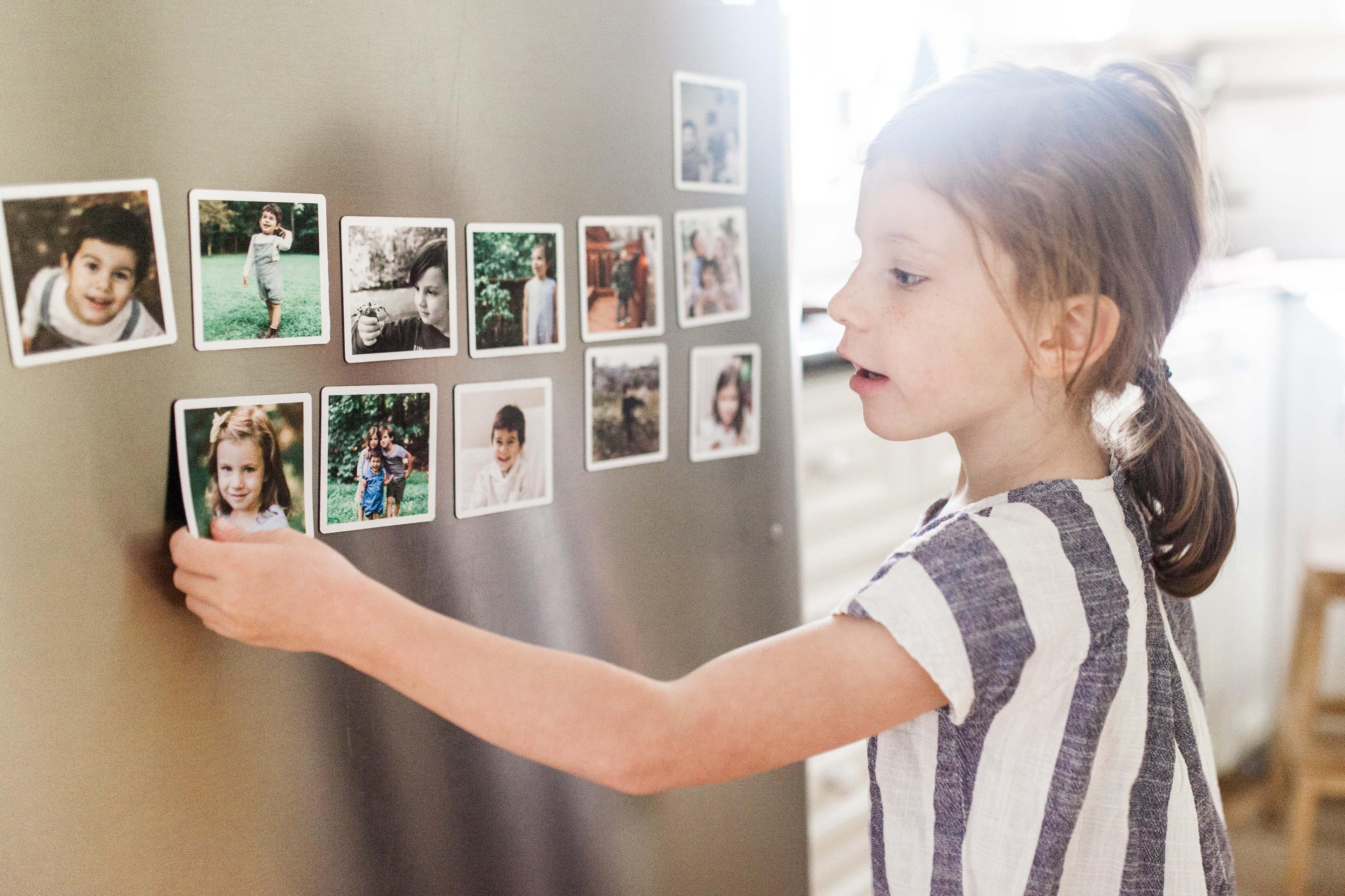 Young girl hanging fridge magnets